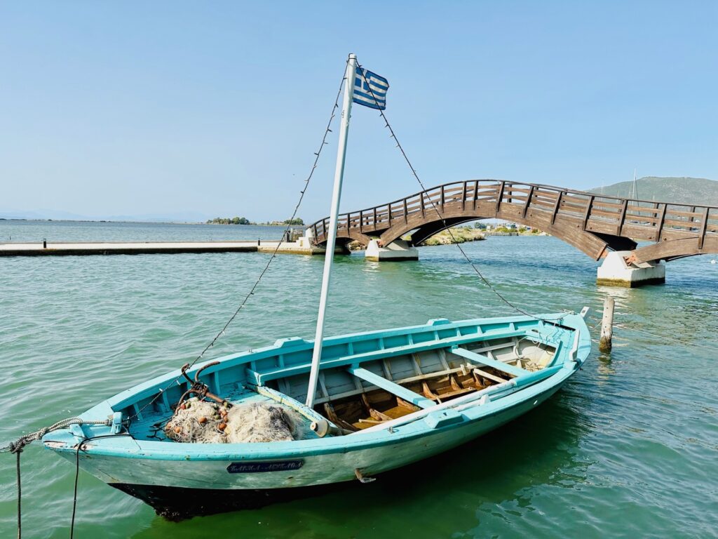 Small boat docked in front of the wooden bridge in Lefkada, Greece