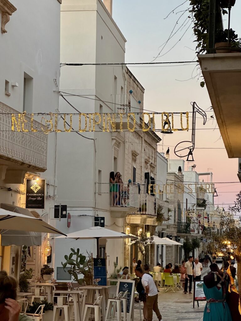 Lyrics to the famous song Volare glistening in lights above Via Roma in Polignano A Mare, Italy